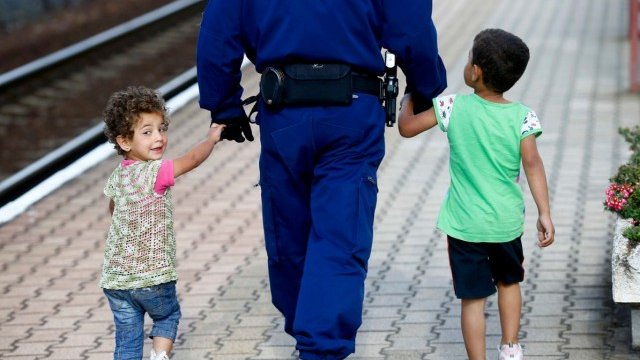 <p>
	Полицай в Мюнхен помага на две деца от Сирия. <em>Снимка: Ройтерс</em></p>
