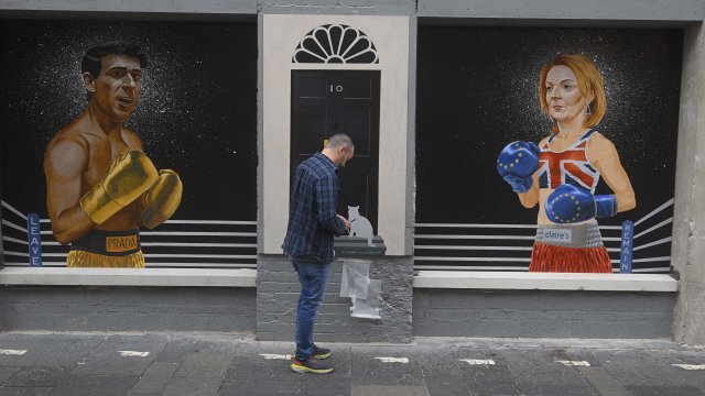 Художникът от Белфаст Киаран Галахър поставя финалните щрихи на стенописа си на претендентите за лидерския пост в Консервативната партия Риши Сунак (вляво) и Лиз Тръс, разделени от вратата на &quot;Даунинг стрийт&quot; 10, в Белфаст, Северна Ирландия, 17 август 2022 г.  Снимка: EPA/Mark Marlow