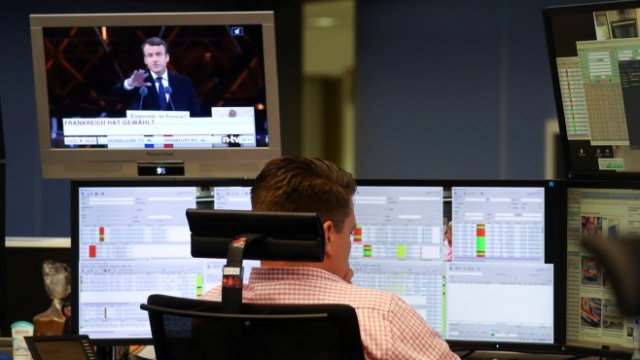 <p>
	Трейдър във Франкфурт следи котировките, докато по телевизора текат новини за победата на Макрон. <em>Снимка: Ройтерс</em></p>
