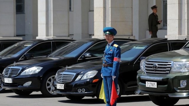 <p>
	Полицай стои пред автомобилите на висши държавни чиновници, паркирани пред&nbsp;Двореца на културата в Пхенян. <em>Снимка: Ройтерс</em></p>

