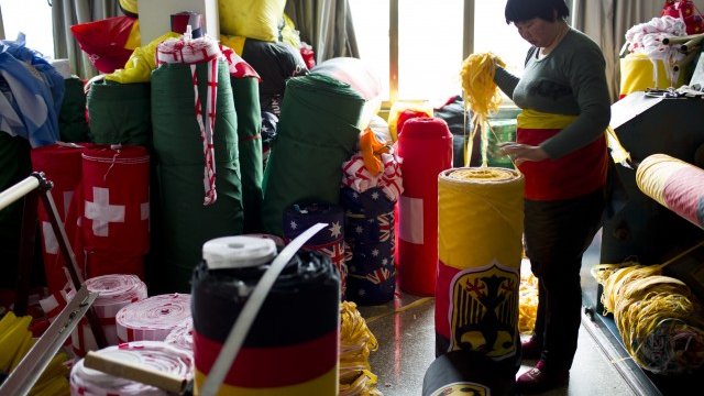 <p>
	Китайска фабрика шие национални знамена, предназначени за продажба по време на предстоящото Световно първенство по футбол в Бразилия. <em>Снимка: Ройтерс</em></p>
