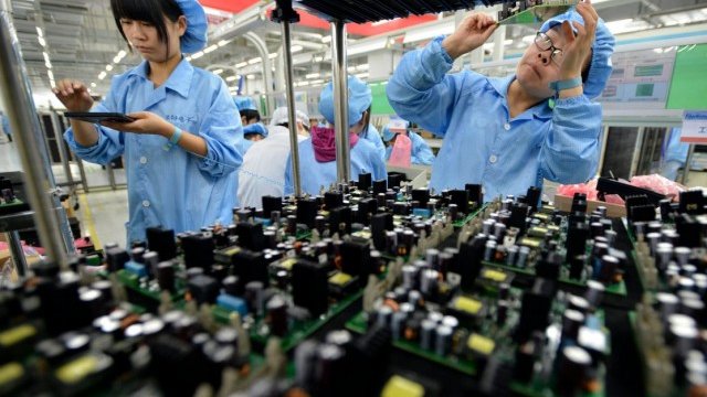 <p>
	Служители в завод за електронни панели на FiberHome Technologies Group в град Ухан.<em> Снимка: Ройтерс&nbsp;</em></p>
