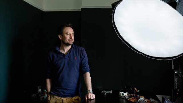 Ейдриън Баркър, основател на уебсайта Bark and Jack, в домашното си студио близо до Глазгоу. Бивш корпоративен обучител, Баркър превръща домашния си канал в YouTube в империя за реклама на луксозни ръчни часовници в рамките на няколко години, като редовно набира стотици хиляди гледания. Снимка: Bloomberg