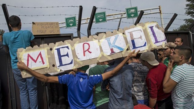 <p>
	Бежанец държи знак с името на Меркел на границата на Унгария <em>Снимка: архив Ройтерс</em></p>
