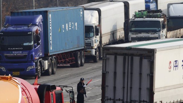 <p>
	Южнокорейски полицай направлява трафика, след като камионите на път за Кесон са принудени да направят обратен завой заради затворения достъп до комплекса. <em>Снимка: Ройтерс</em></p>
