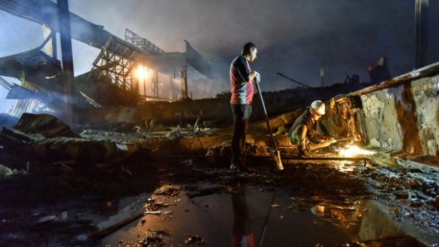 <p>
	&nbsp;Пожарникар и доброволец гасят пожара в мола в град Кременчук. <em>Снимка: EPA/OLEG PETRASYUK</em></p>
