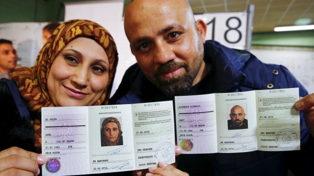 <p>
	Бежанци от Сирия позират с издадените им в Германия документи. <em>Снимка: Ройтерс</em></p>

