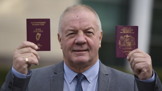 <p>
	Реймънд МакКорд позира пред медиите със своите ирландски и британски паспорти, след като е получил новия си документ от службите в Белфаст. <em>Снимка: Ройтерс</em></p>
