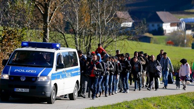 <p>
	Полицаи ескортират мигранти към център за регистрация. <em>Снимка: Ройтерс</em></p>
