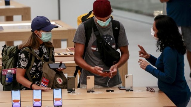 <p>
	Посетители на магазин на концерна в Сингапур говорят със служител на Apple. <em>Снимка: EPA/WALLACE WOON</em></p>
