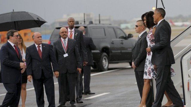 <p>
	Американският президент Барак Обама и съпругата му Мишел са посрещнати от кубинския външен министър Бруно Родригес (вляво) при кацането на Еърфорс 1 за тридневната визита на Обама в Куба. <em>Снимка: Ройтерс</em></p>
