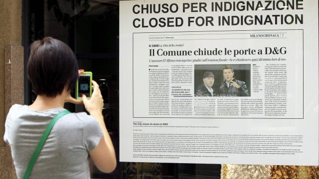 <p>
	Хора минават покрай прозорец на затворен в знак на протест магазин на Dolce&amp;Gabbana в Милано. <em>Снимка: Ройтерс</em></p>
