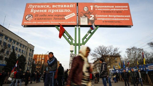 <p>
	Проруски демонстранти пред постер, изобразяващ призив от Втората Световна война в комбинация с актуално послание, в Луганск, Източна Украйна. <em>Снимка: Ройтерс</em></p>
