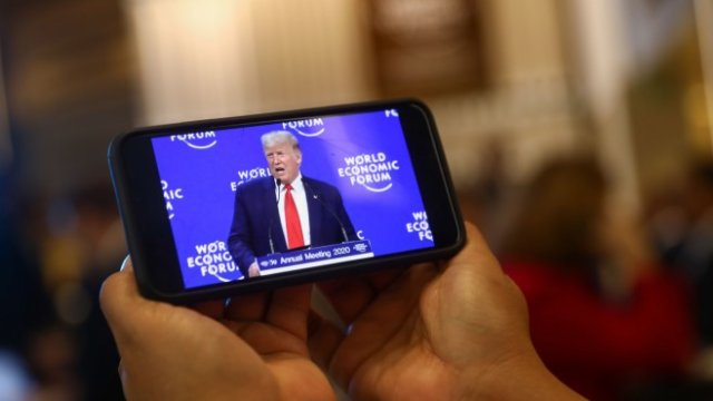 <p>
	Зрител следи речта на американския президент Доналд Тръмп в Давос. <em>Снимка: Bloomberg</em></p>
