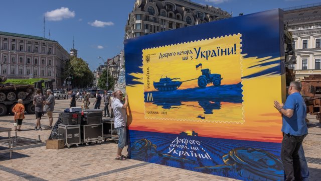Работници държат транспарант на нова пощенска марка с надпис &quot;Добър вечер, ние сме от Украйна!&quot; на Михайловския площад в Деня на украинската държавност в Киев, Украйна, 28 юли 2022 г. Снимка: EPA/ROMAN PILIPEY