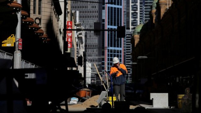 <p>
	<em>Австралийски работник в Сидни пуши цигара, докато си гледа телефона, Снимка: Ройтерс</em></p>
