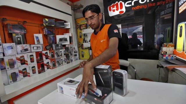 <p>
	Служител на индийската MicroMax подрежда телефони в магазин на компанията.<em> Снимка: Ройтерс</em></p>
