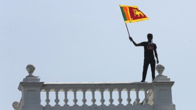 <p>
	Протестиращ вее националния флаг от балкона на премиерския офис. <em>Снимка:&nbsp;&nbsp;EPA/CHAMILA KARUNARATHNE</em></p>
