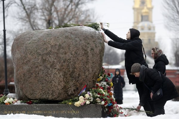 Хора полагат цветя и палят свещи до снимката на Алексей Навални до мемориала на политическите затворници в Санкт Петербург. Снимка: БГНЕС/ EPA/ANATOLY MALTSEV