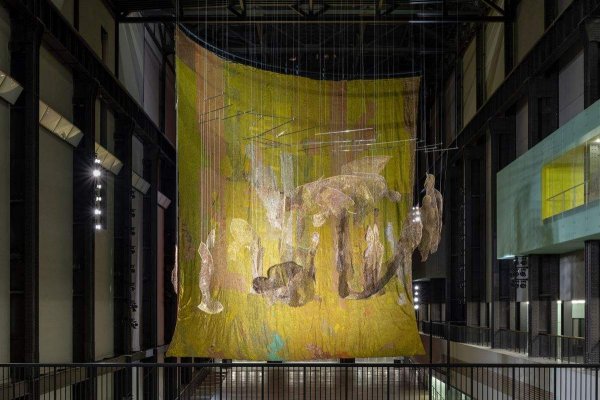 Годишната комисия Hyundai на Tate Modern представя произведение, или поредица от произведения, направени специално за залата Turbine Hall на музея. Предишните поръчки със сигурност са били големи, но никога не са имали монументалността на металните гоблени на Ел Анацуи.

Изработени от капачки на бутилки за алкохол и малки парчета метал, три произведения се издигат до горните греди на сградата.

Анацуи е един от най-интересните съвременни художници. Практиката на ганайския скулптор е заета с история, география и индустрия. 

Въпреки че инсталацията на Tate е предназначена да функционира като история в три действия, тя също е, за радост на посетителите, визуално зашеметяваща скулптура - каквато Лондон никога не е виждал.
