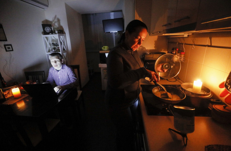 Украинско семейство готви вечеря с помощта на туристическа печка "Примус" по време на планираното спиране на тока в Киев. Снимка: ЕРА
