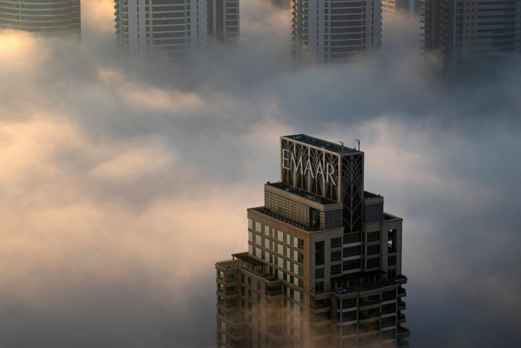 Сутрешна мъгла обвива табелата на Emaar върху небостъргач в квартал "Дубай Марина". Снимка: Кристофър Пайк/Bloomberg