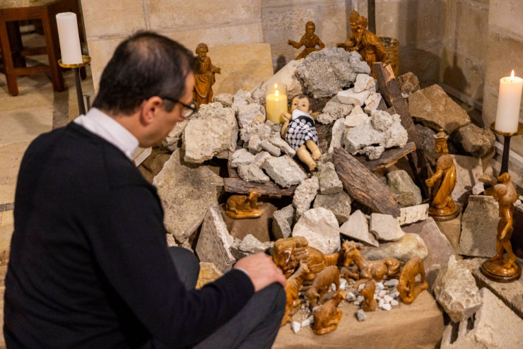 На олтара в евангелската лутеранска църква във Витлеем е изложена преработена сцена на Рождество Христово. Фигурата на младенеца Исус, увито в палестинска куфия, е поставена върху купчина отломки. Снимка: Мaja Hitij/Getty Images