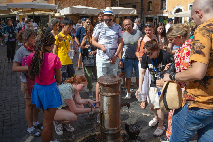 Хора са се събрали около чешма в горещо време в Рим миналия месец. Снимка: Bloomberg