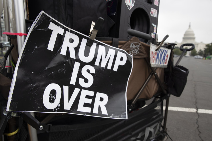 Контрапротестиращ с надпис „С Тръмп е свършено", а зад него се вижда Капитолия, докато хората започват да пристигат за протест във Вашингтон. Снимка:  EPA/MICHAEL REYNOLDS
