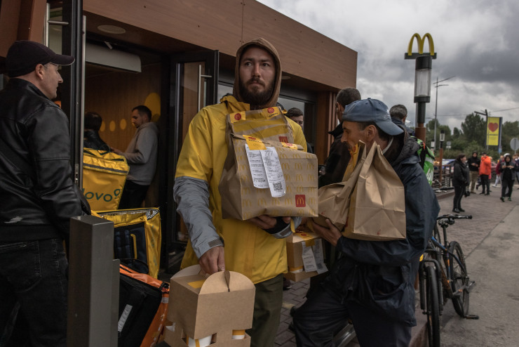 Десетки куриери на Glovo събират поръчки от отворените отново в Киев обекти на McDonald&#39;s. EPA/ROMAN PILIPEY