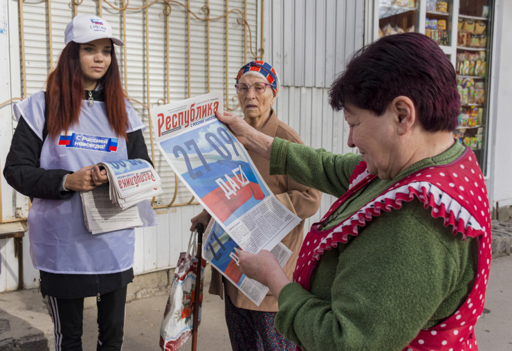 Доброволец разпространява предизборен вестник "Република" с надпис "27.09 - Да" по време на предизборен митинг за референдума за присъединяване към Руската федерация в центъра на Луганск, Украйна, 22 септември 2022 г. Снимка:  EPA/STRINGER