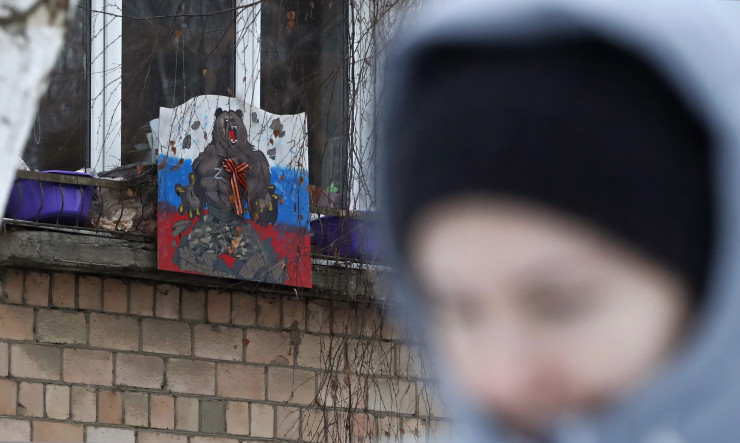  Жена минава покрай опънато в жилищен блок знаме на Русия в Москва. Снимка: EPA/MAXIM SHIPENKOV